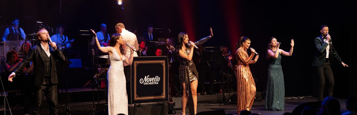 Singers onstage performing in front of an orchestra.