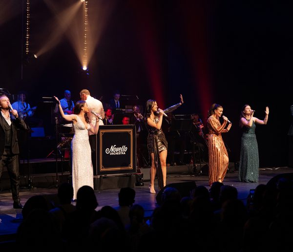 Singers onstage performing in front of an orchestra.