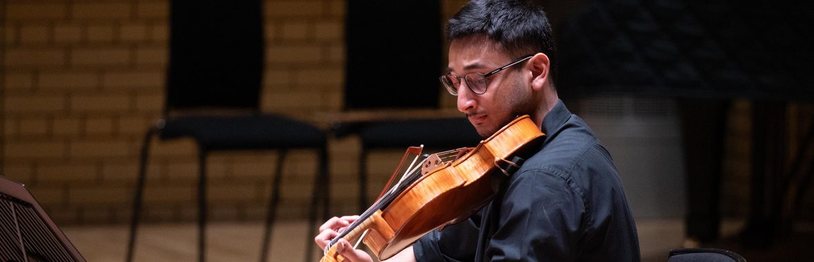 Man with short dark hair playing a string instrument.
