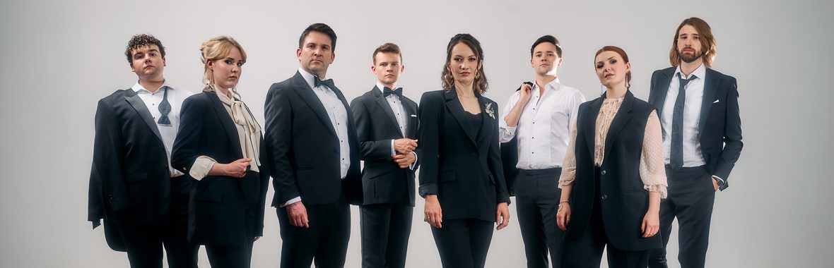 Group of men and women standing wearing smart clothing against a white background.
