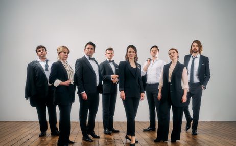 Group of men and women standing wearing smart clothing against a white background.