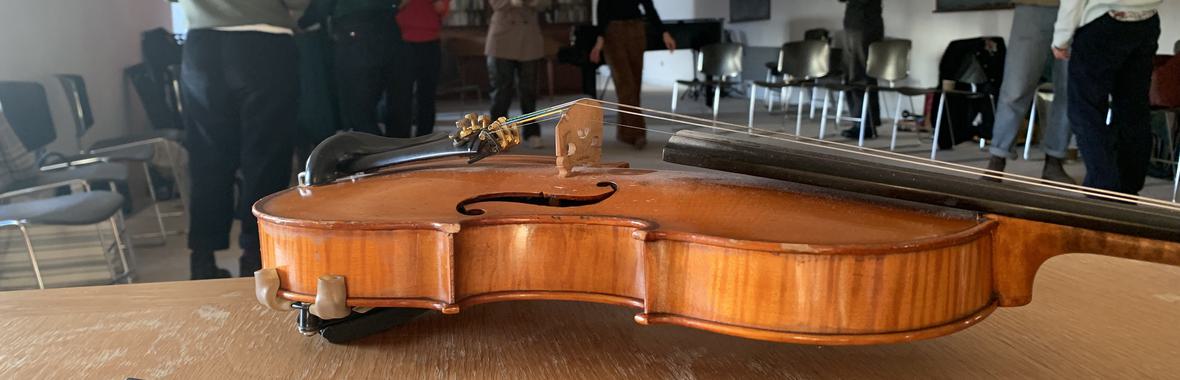 Close up of violin with people talking in the background.