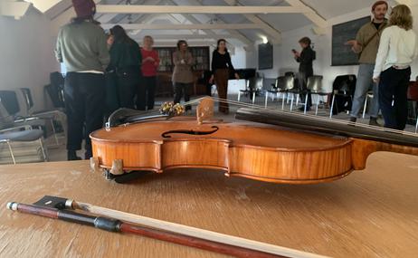 Close up of violin with people talking in the background.
