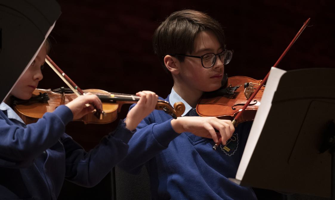 Boy wearing school uniform playing the violin.