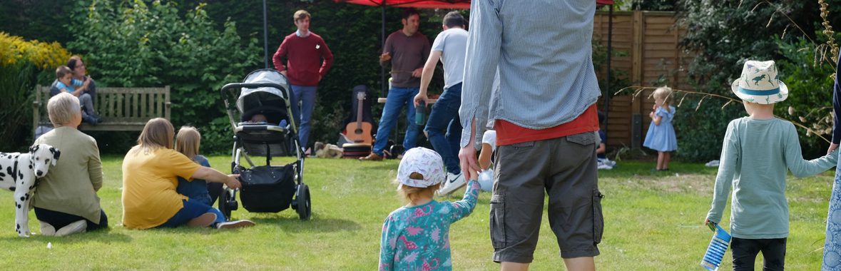 A child holding hands with their guardian in a garden.