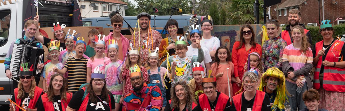Group of adults and children dressed up in carnival clothes and colourful make-up.