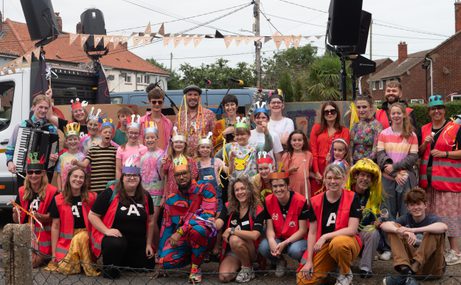 Group of adults and children dressed up in carnival clothes and colourful make-up.