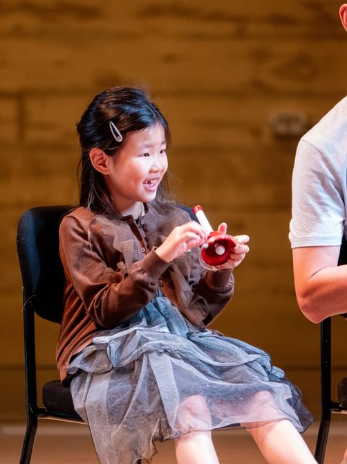 Young girl sitting smiling and holding a musical instrument
