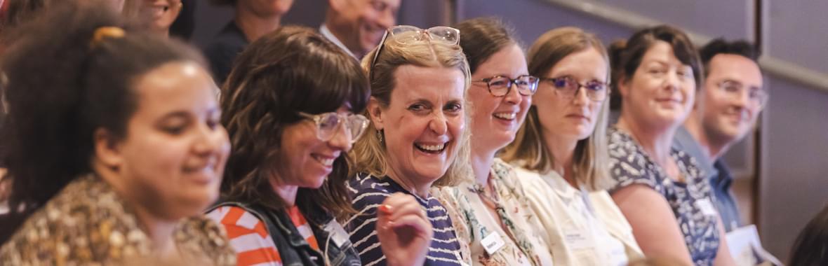 Group of people sitting in an audience setting together and smiling.