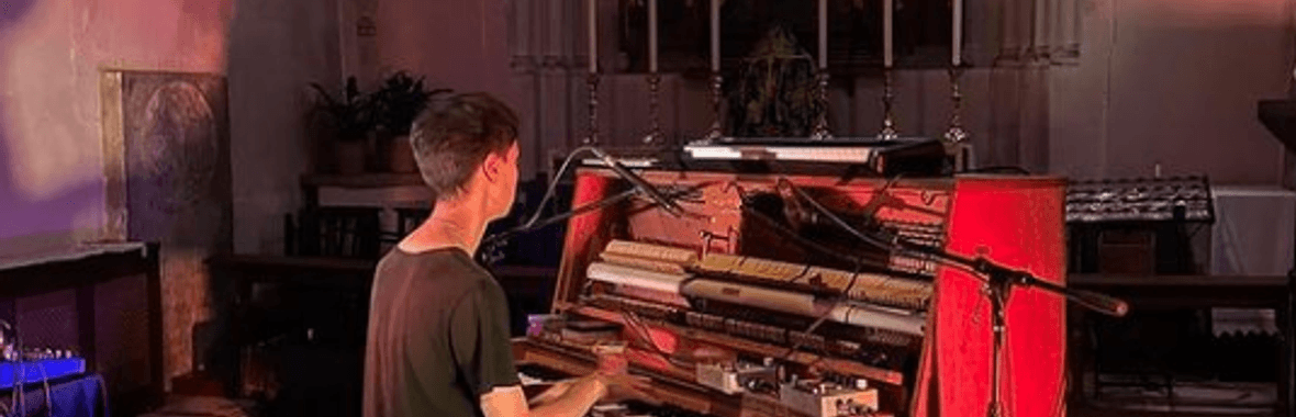Theo Alexander playing a piano in red lighting