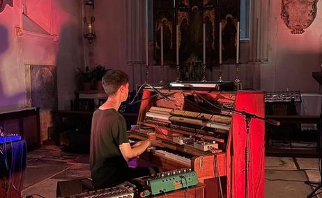 Theo Alexander playing a piano in red lighting