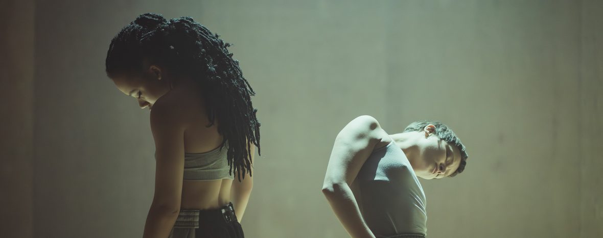 Two dancers leaning their heads to one side away from the camera