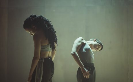 Two dancers leaning their heads to one side away from the camera
