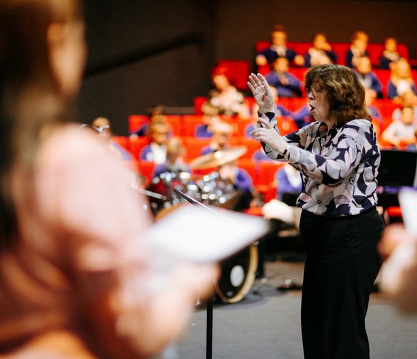 A person conducting a group of children who are singing.