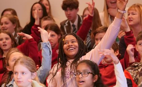 A group of children smiling and raising their hands.