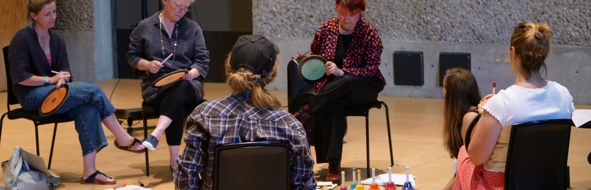 A group of people sat in a circle with instruments