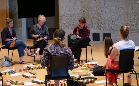 A group of people sat in a circle with instruments