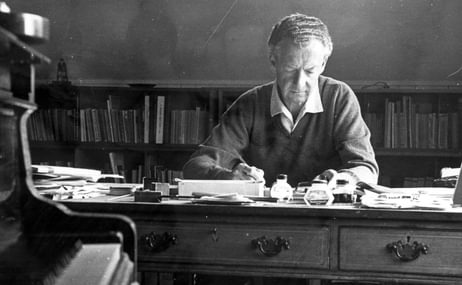 Benjamin Britten sitting at a desk writing on paper.